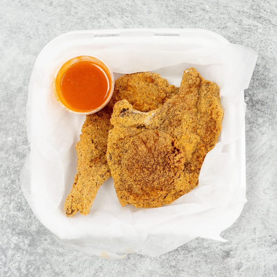 Fried fish fillets and a cup of dipping sauce in a white takeout container.