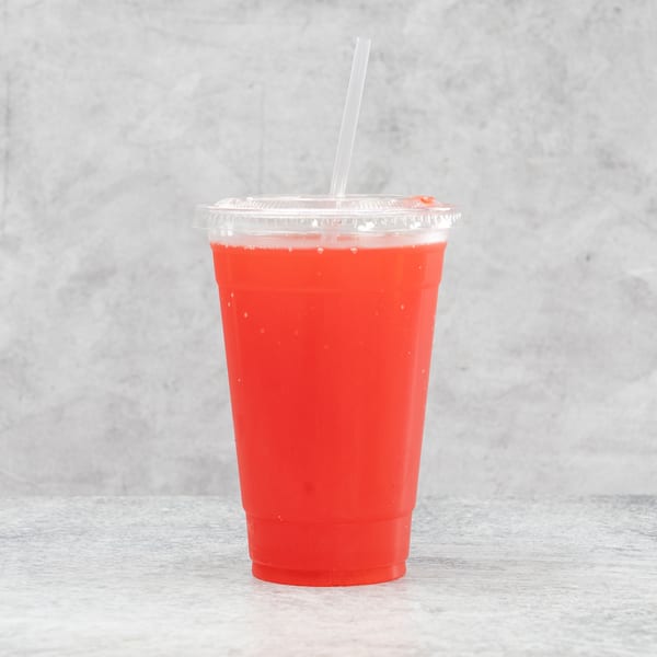 Bright red beverage in a clear plastic cup with a straw, against a gray background.